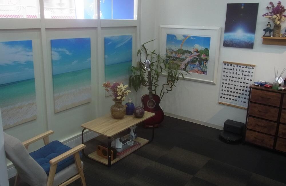 shop03 Cozy room corner with ocean beach wall art, a wooden table with vases and plants, and a red guitar by the plant stand-inside a calm workspace.